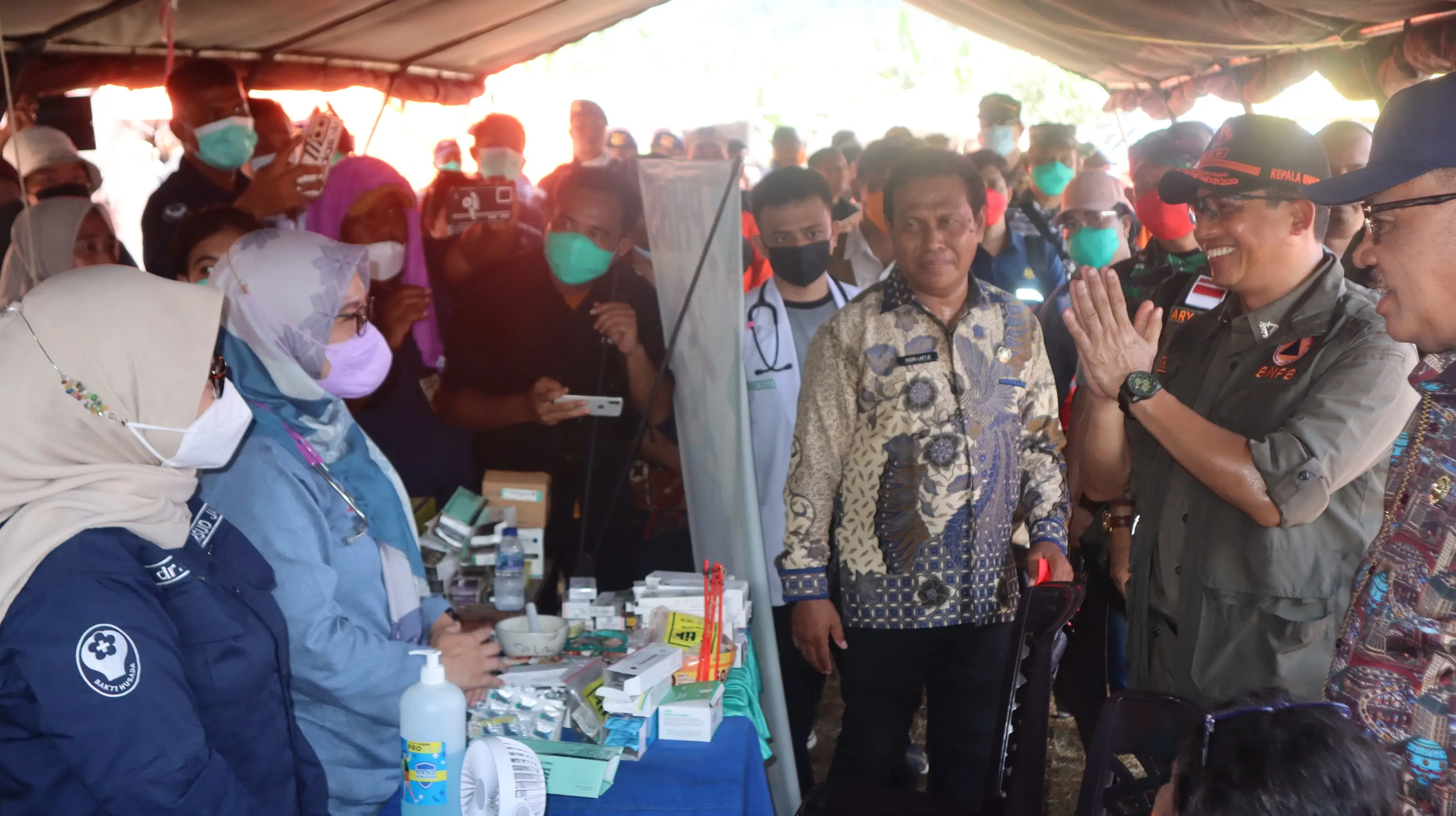 Kepala BNPB Letjen TNI Suharyanto, S. Sos., M.M (kemeja dan rompi hijau) saat berdiskusi dengan tim kesehatan yang bertugas di posko pengungsian Desa Gam Ici, Kabupaten Halmahera Barat, Maluku Utara pada Kamis (30/5).